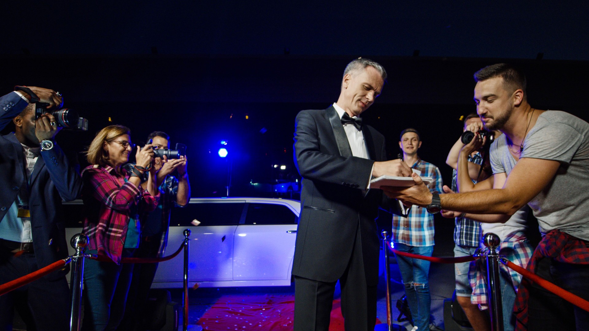 Adult celebrity giving autographs on red carpet