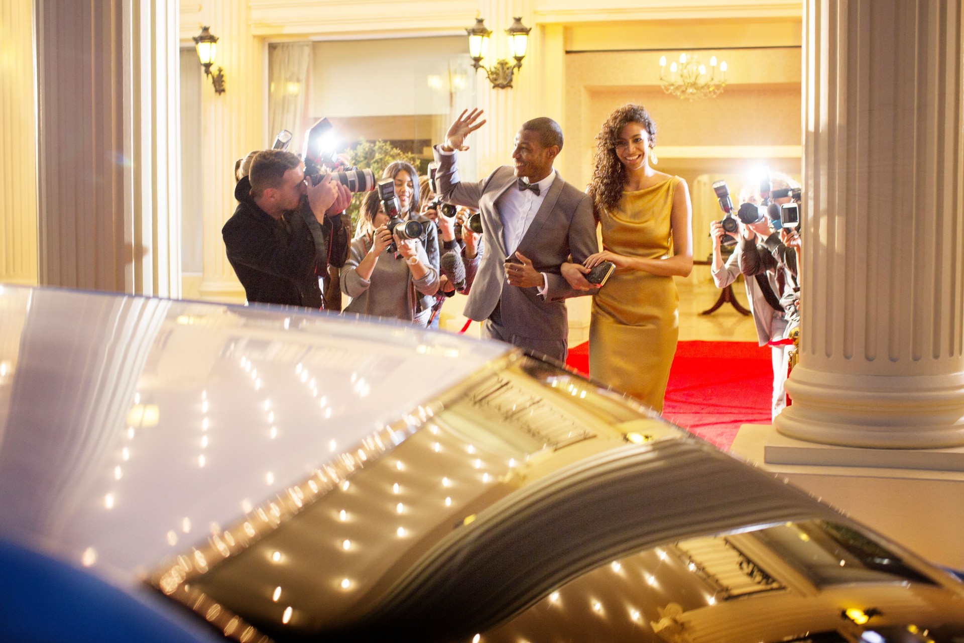 Celebrity couple waving at paparazzi photographers and leaving event